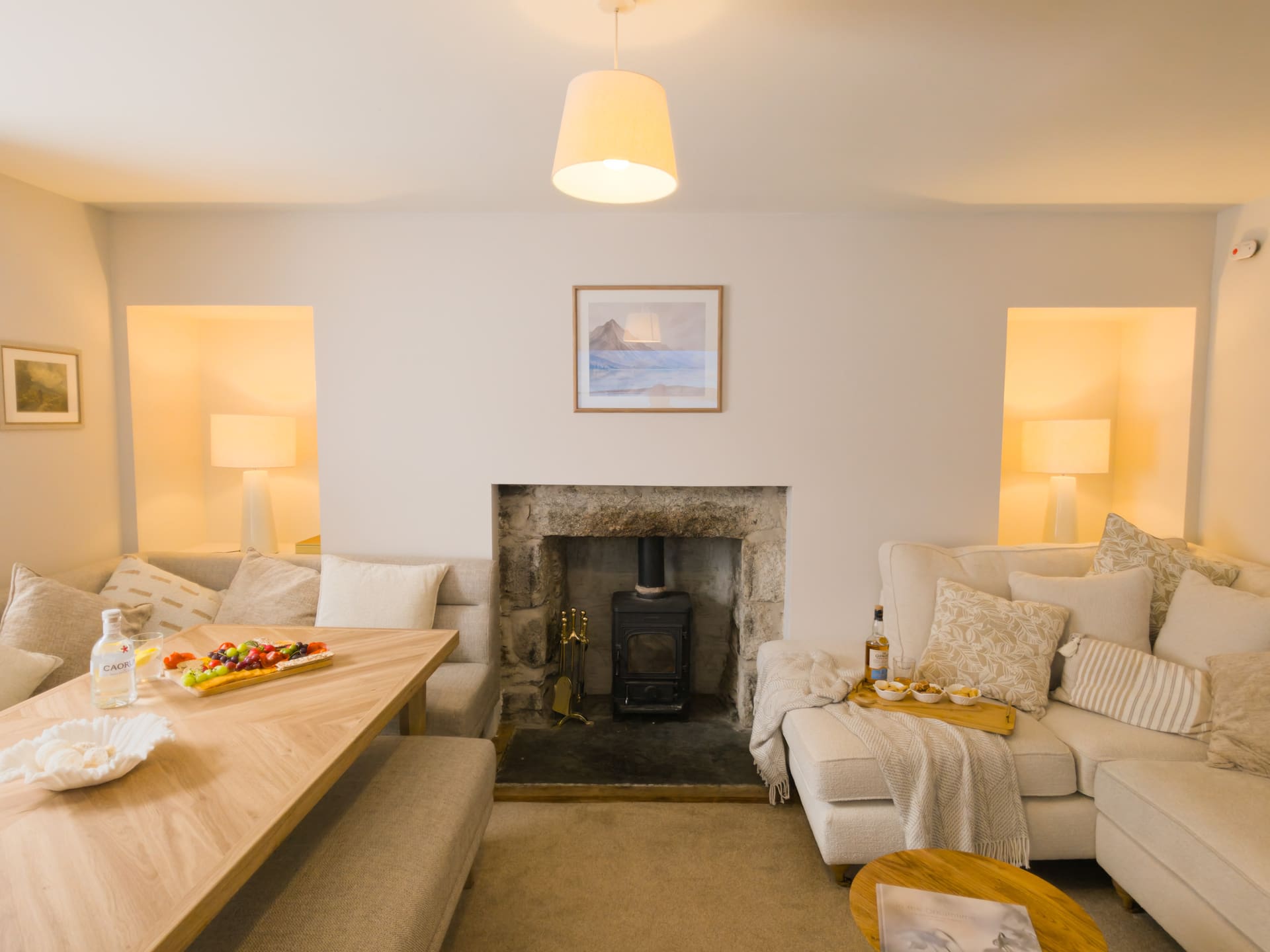 The sitting room at The Twinflower, with a stone fireplace and cream sofas
